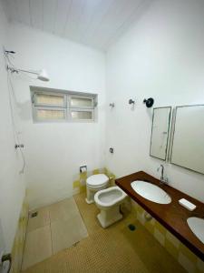 un bagno con due lavandini, un water e uno specchio di Casa na Praia dos Pesacdores a Itanhaém Altre 9 foto