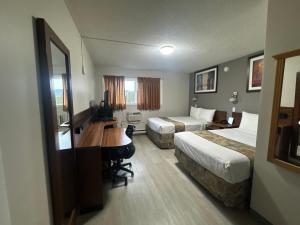 een hotelkamer met twee bedden en een bureau bij Canadas Best Value Inn Kelowna in Kelowna