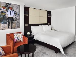 a hotel room with a bed and a chair at Mövenpick Hotel Jumeirah Lakes Towers Dubai in Dubai