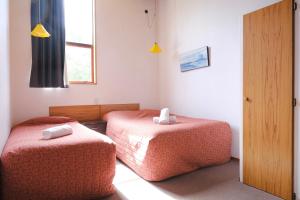 a room with two beds and a window and a door at Forest Trail Lodge in Hanmer Springs +17 photos