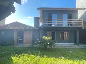 a house with a balcony and a plant in the yard at Casa com piscina in Tramandaí