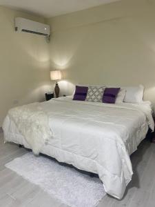 a bedroom with a large white bed with purple pillows at Mayra House habitación independiente cerca del aeropuerto las Américas TAXI DISPONIBLE in Andrés