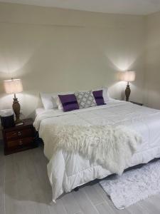 a bedroom with a large bed with white sheets and purple pillows at Mayra House habitación independiente cerca del aeropuerto las Américas TAXI DISPONIBLE in Andrés