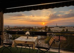 een tafel en stoelen op een balkon met een zonsondergang bij London apartments 2 in Pristina
