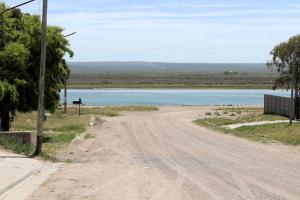 een verlaten zandweg naast een waterlichaam bij Clau Propiedades in San Antonio Oeste