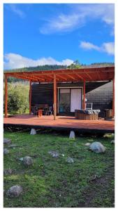 a house with a deck with a table and chairs at Achibueno Glamping in Linares