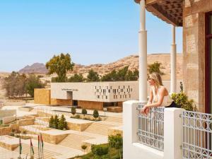 a woman sitting on a ledge of a building at Mövenpick Resort Petra in Wadi Musa
