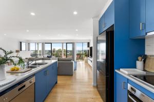 a kitchen with blue cabinets and a living room at Hazel Beach House - Ocean Views & Coastal Charm in Goolwa South