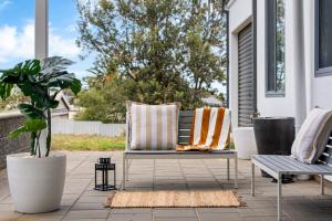 a porch with a bench and two pillows on it at Hazel Beach House - Ocean Views & Coastal Charm in Goolwa South