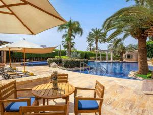 a patio with a table and chairs and a pool at Mövenpick Resort & Residences Aqaba in Aqaba +238 photos