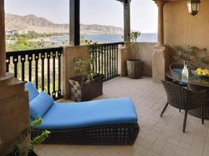 een balkon met een tafel en stoelen en uitzicht op de oceaan bij Mövenpick Resort & Residences Aqaba in Aqaba