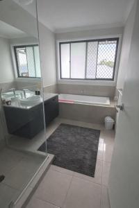 a bathroom with a tub and a sink and a shower at Comfortable Home stay in Pimpama