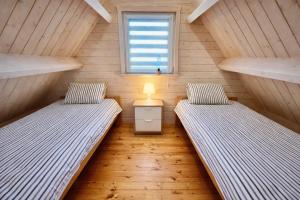 two twin beds in a room with a window at Domeczki Blaneczki Wicie - domki letniskowe nad morzem in Wicie