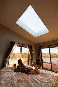une femme dormant sur un lit devant une fenêtre dans l'établissement Grand Canyon Stargazing Off-Grid, à Williams