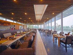 een restaurant met lange tafels, banken en ramen bij Fairmont Yangcheng Lake in Kunshan