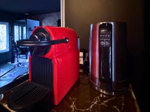 Een rode koffer staat op het aanrecht naast een koffiezetapparaat. bij Hmm OH Oui - Studio With Sauna and More in Saint-Quentin