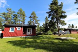 a red cabin with a black roof in a yard at Aurora Jukkasjarvi in Jukkasjärvi