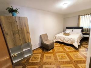 a bedroom with a bed and a chair in it at Laguna Apartment in Huaraz
