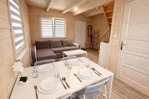 a tiny house with a white table and chairs at Domeczki Blaneczki Wicie - domki letniskowe nad morzem in Wicie