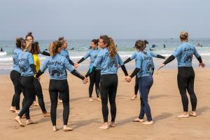 un gruppo di donne in piedi sulla spiaggia che si tengono per mano di Mabidi Surf Taghazout a Taghazout