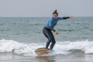 Una donna che cavalca un'onda su una tavola da surf nell'oceano di Mabidi Surf Taghazout a Taghazout