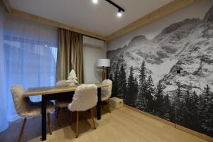 a room with a table and chairs with a mountain mural at Wierchy Resort 21B by AWapartaments in Zakopane