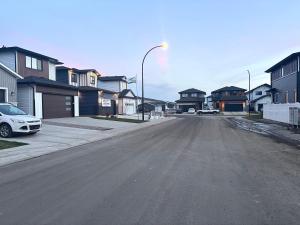 an empty street in a residential neighborhood with houses at Cozy Heaven in Saskatoon