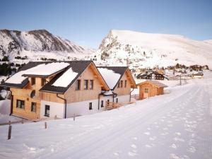een dorp bedekt met sneeuw met bergen op de achtergrond bij Designchalets Falkertsee in Ebene Reichenau