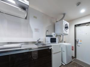 a small kitchen with a sink and a microwave at Hote Io Lite in Nago