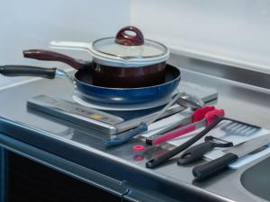 a pot sitting on top of a stove with cooking utensils at Hote Io Lite in Nago