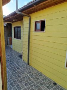 een gele muur van een gebouw met twee ramen bij Departamento Mar y Viento in Pichilemu