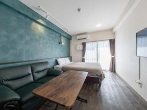 a room with a couch and a bed and a table at Hote Io Lite in Nago