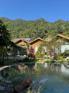 a house with a pond in front of it at Mộc Sơn Homestay in Mộc Châu