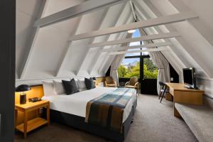 Un dormitorio con una cama, un escritorio y un televisor. en Heartland Hotel Queenstown, en Queenstown