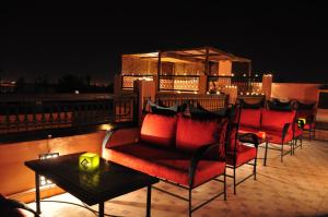a group of chairs and tables on a balcony at night at Riad Imilchil in Marrakesh