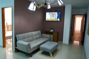 een woonkamer met een bank, een kruk en een televisie bij Gairaka 5 in Gaira