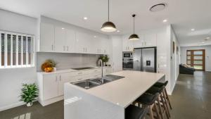 een witte keuken met een wastafel en een aanrecht bij Bella Callala in Callala Beach