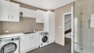 een keuken met witte kasten en een wasmachine en droger bij Bella Callala in Callala Beach