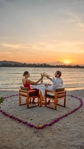 a man and woman sitting at a table on the beach at BASK Gili Meno in Gili Meno