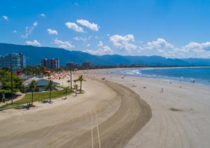een strand met veel mensen en de oceaan bij Casa térrea a 1km da praia com ar condicionado in Bertioga