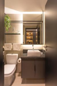 een badkamer met een wastafel, een toilet en een spiegel bij Flat novo de luxo na melhor área da praia de Ponta de Campina! in Cabedelo