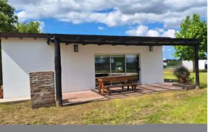 une petite maison blanche avec une table de pique-nique sur une terrasse dans l'établissement Cabañas Don Ricardo, à Dolores