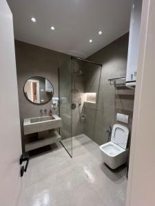 een badkamer met een toilet, een wastafel en een spiegel bij Central Tirana Apartments in Tirana