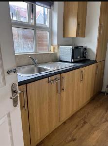 een keuken met een spoelbak en een magnetron bij Abidjan in Feltham