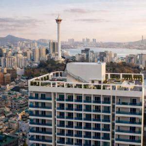 eine Stadtsilhouette mit einem hohen weißen Gebäude und einem Turm in der Unterkunft Magnum Nampo Hotel in Busan