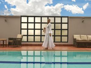 a woman in a white dress standing next to a swimming pool at Pullman Nairobi Upper Hill in Nairobi