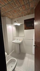 een witte badkamer met een wastafel en een toilet bij La Dorada Inn in Luján