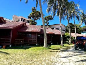 een rood huis met palmbomen ervoor bij Redang Divers Resort in Redang Island +9 foto's