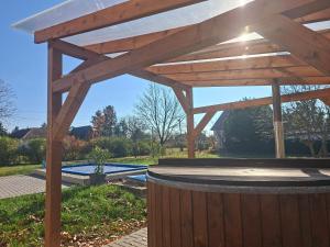 a wooden pergola with a pool in a yard at Szárcsa Apartman Sarud in Sarud