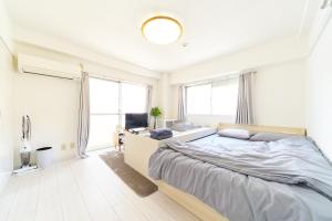 a white bedroom with a large bed and windows at Maison Junes 21 in Tokyo